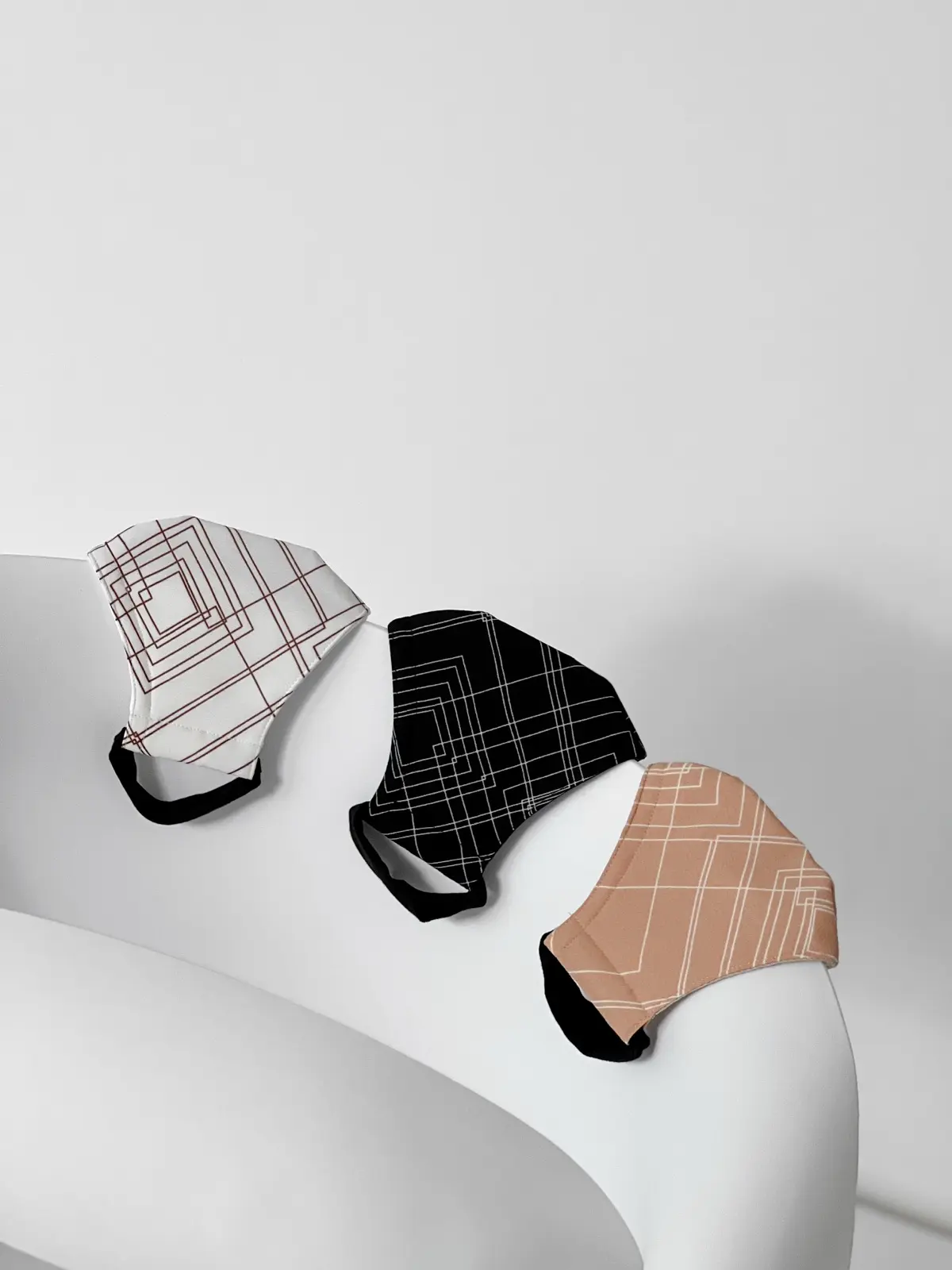 White, black and peach masks with fine line prints on white paper