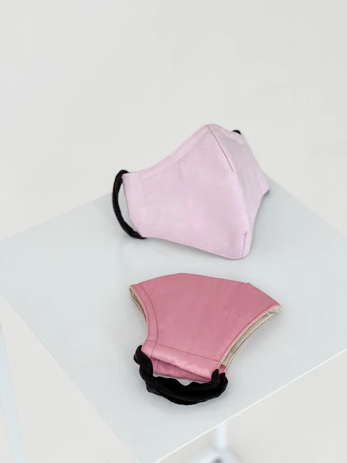 Two pink masks on a white plinth