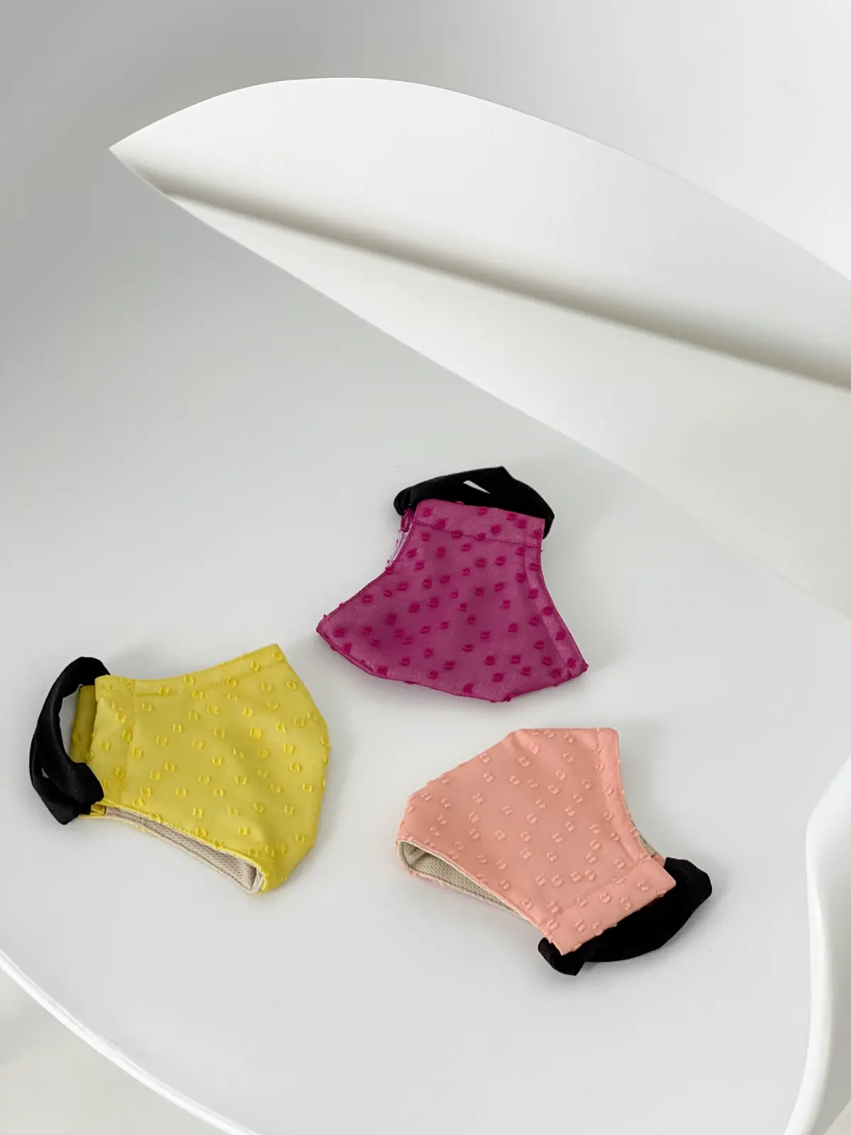 Yellow, magenta and peach textured masks on white paper