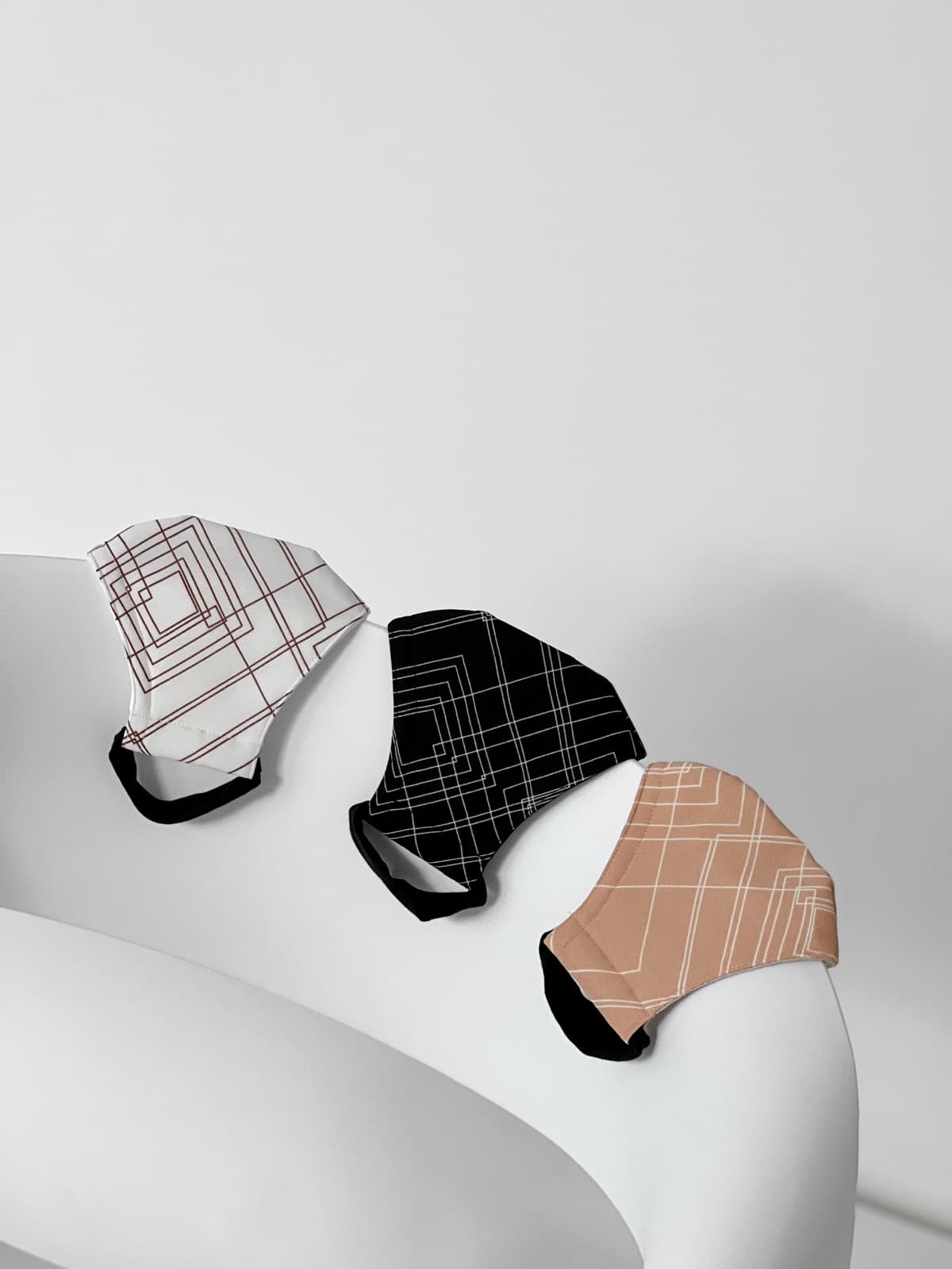 White, black and peach masks with fine line prints on white paper